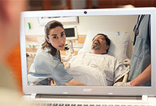 Eine Pflegekraft k&uuml;mmert sich am Bett um einen Patienten.