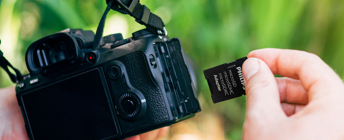 Eine Person h&auml;lt eine Kamera in der einen Hand und eine Speicherkarte in der anderen, bereit, Momente einzufangen.