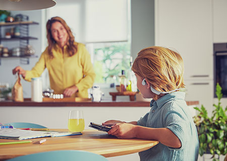 Gar&ccedil;on portant un casque pour enfants Philips open-ear sans fil et regardant une vid&eacute;o
