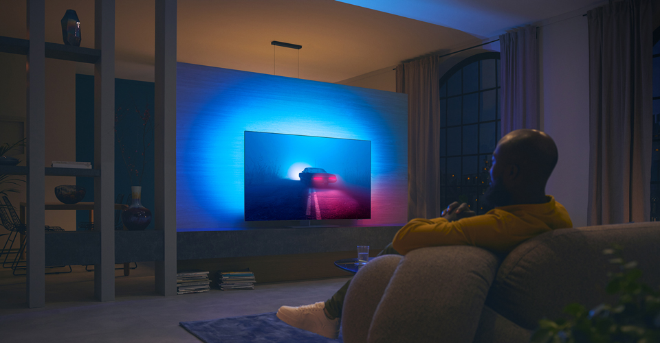 Ein Paar sieht sich einen Film auf einem Ambilight-TV an